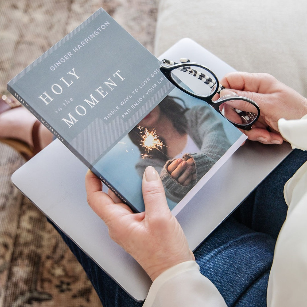 Copy of book, Holy in the Moment, is on a table alongside a cup of coffee.